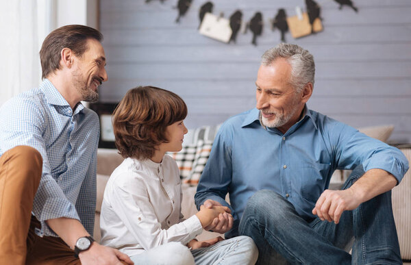 Cheerful positive man shaking his grandsons hand
