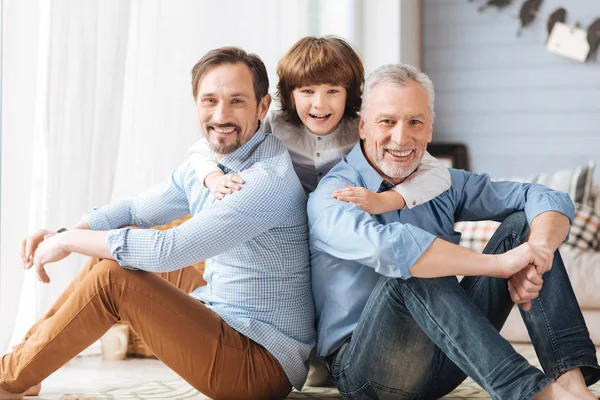 Cute delighted child hugging his father and grandfather — Stock Photo, Image
