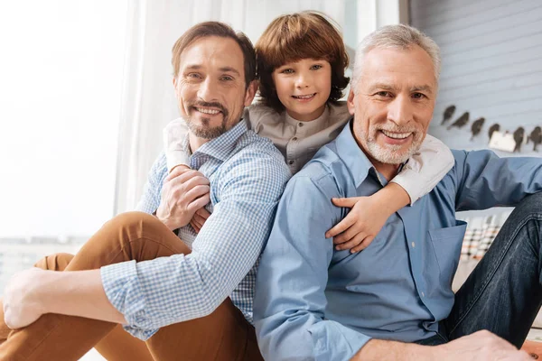 Agradable chico encantado abrazando a su familia — Foto de Stock