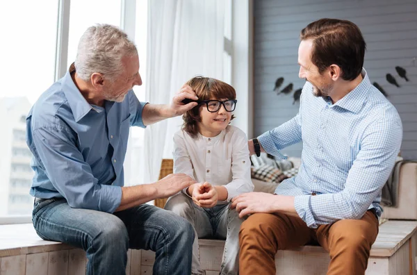 Nice aged man fixing his grandsons glasses — Stock Photo, Image