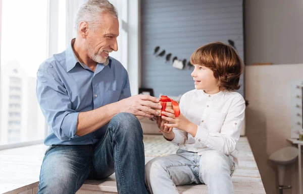 Homme âgé joyeux donnant un cadeau à son petit-fils — Photo