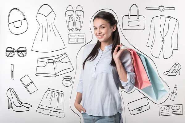 Mujer alegre sosteniendo bolsas de compras sobre fondo gris — Foto de Stock