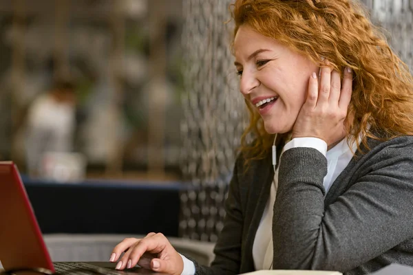 Donna piacevole allegra utilizzando il computer portatile nel caffè — Foto Stock