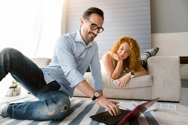 Energisk par sitter och använder bärbar dator hemma — Stockfoto
