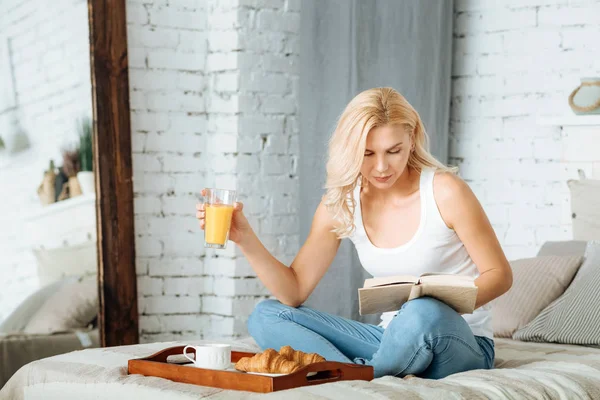 Woman reading book in bed — Stock Photo, Image