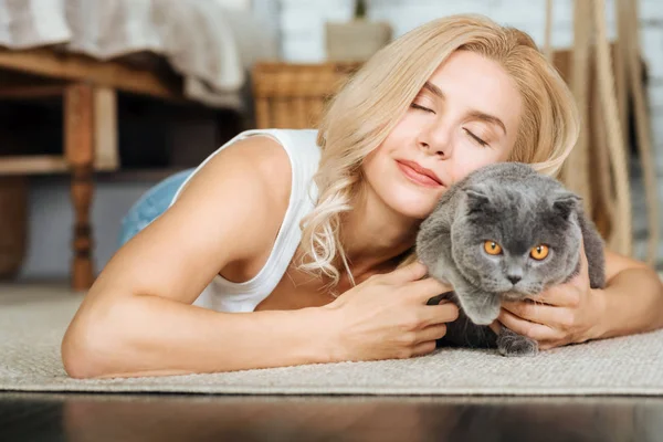 Frau liegt mit ihrer Katze auf dem Boden — Stockfoto