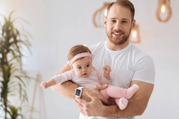 Положительный отец держит ребенка на руках у себя дома — стоковое фото