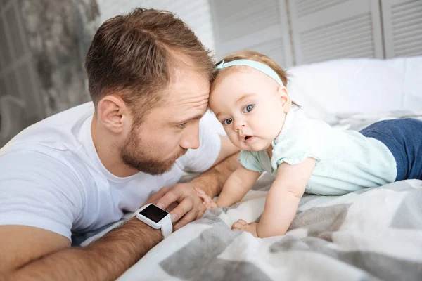 Verspieltes kleines Mädchen, das sich mit seinem Vater im Schlafzimmer ausruht — Stockfoto