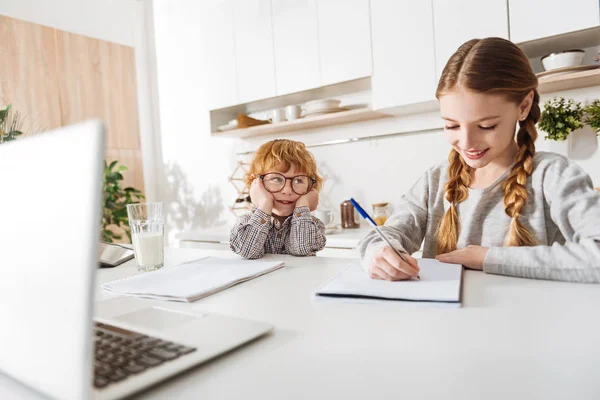 Encantador niño viendo a su hermana estudiando — Foto de Stock