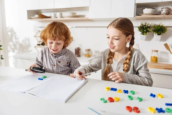 Süßer heller Junge hilft seiner Schwester bei den Hausaufgaben — Stockfoto