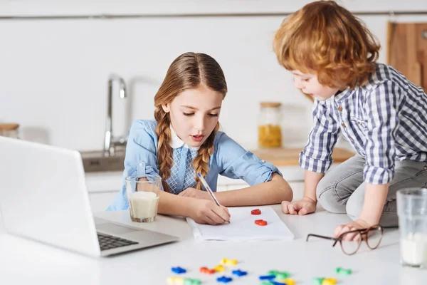 Menina diligente inteligente explicando seus cálculos básicos irmão — Fotografia de Stock