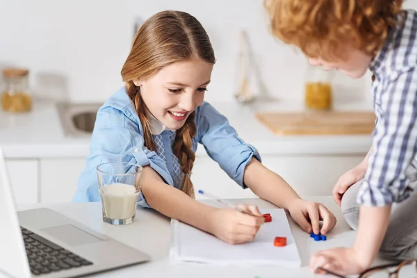 Menina inteligente feliz fazendo lição de casa com seu irmão — Fotografia de Stock