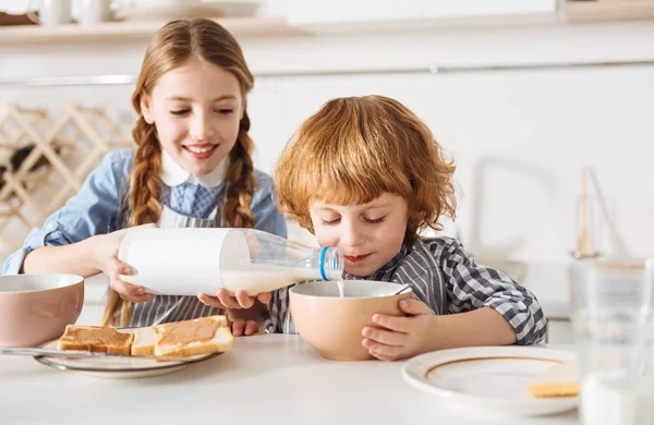 Sonriente chica encantadora vertiendo leche en un tazón — Foto de Stock