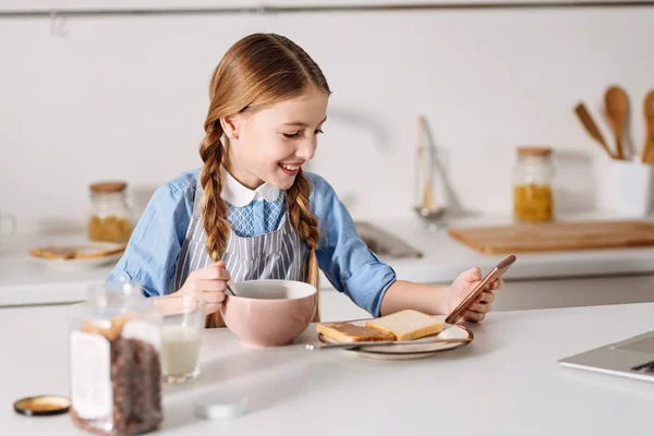 Menina entusiasta inteligente ler notícias durante o café da manhã — Fotografia de Stock