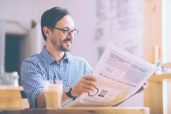 Ευχάριστη γενειοφόρος άνδρας διαβάζει εφημερίδα στο καφενείο — Φωτογραφία Αρχείου