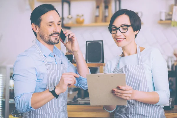 Joyful couple of cafe owners talkign on smart phone — Stock Photo, Image