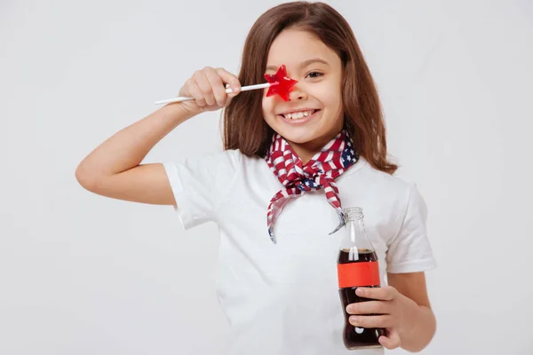 Feliz niña sosteniendo botella y piruleta en el estudio —  Fotos de Stock