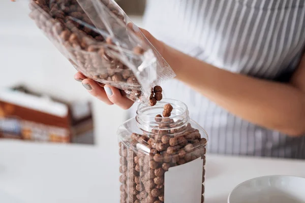 Neat girl putting chocolate chips into a jar — Stock Photo, Image