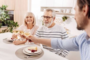Yaşlı çift ile onların çocuk evde akşam yemeği relishing gülümseyen
