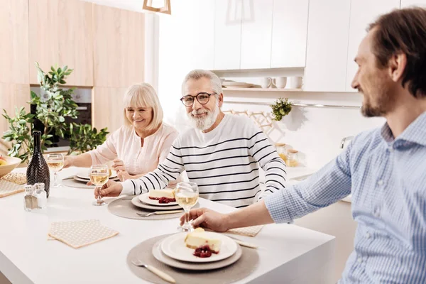 Positive elderly parents enjoying weekend with son at home