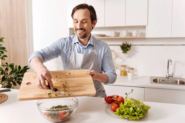 Задоволений бородатий чоловік готує овочевий салат — стокове фото