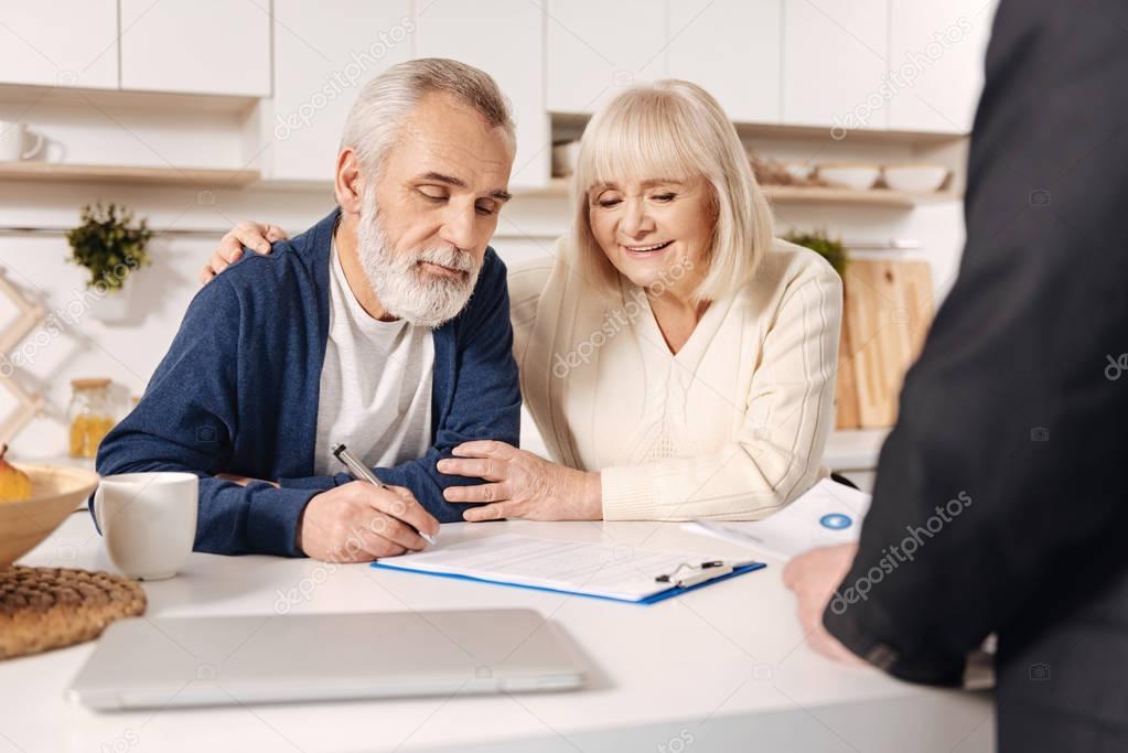 Delightful elderly couple signing documents 