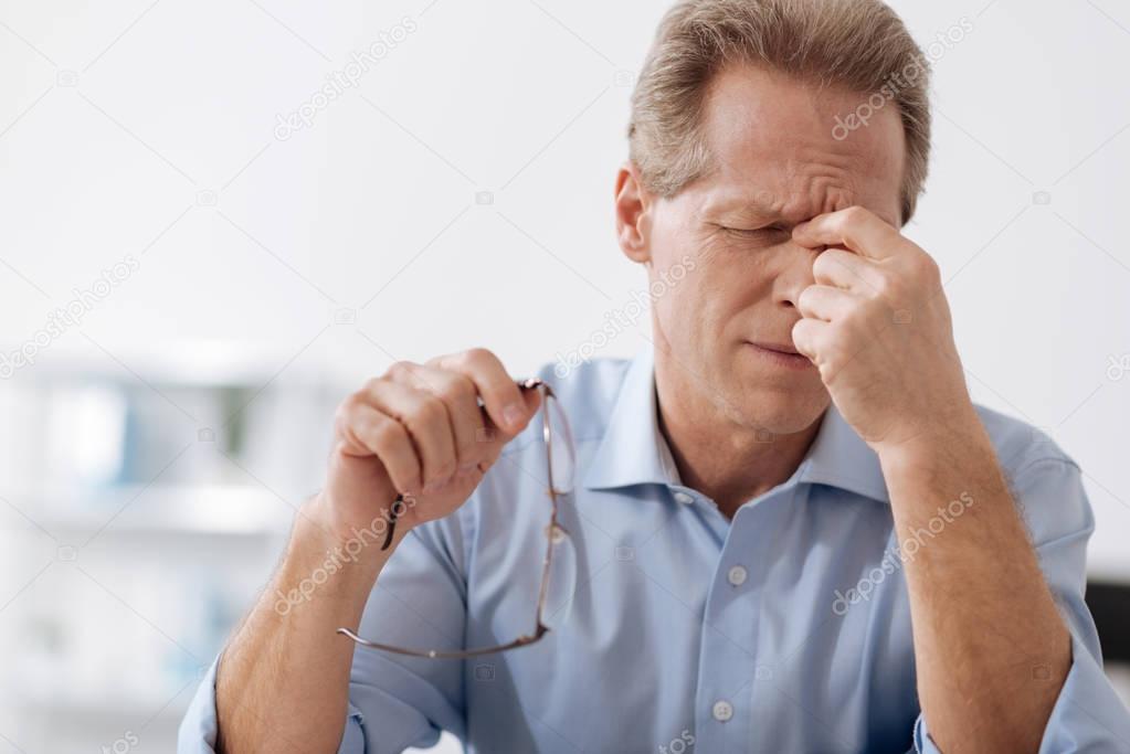 Disappointed male person touching his bridge of nose