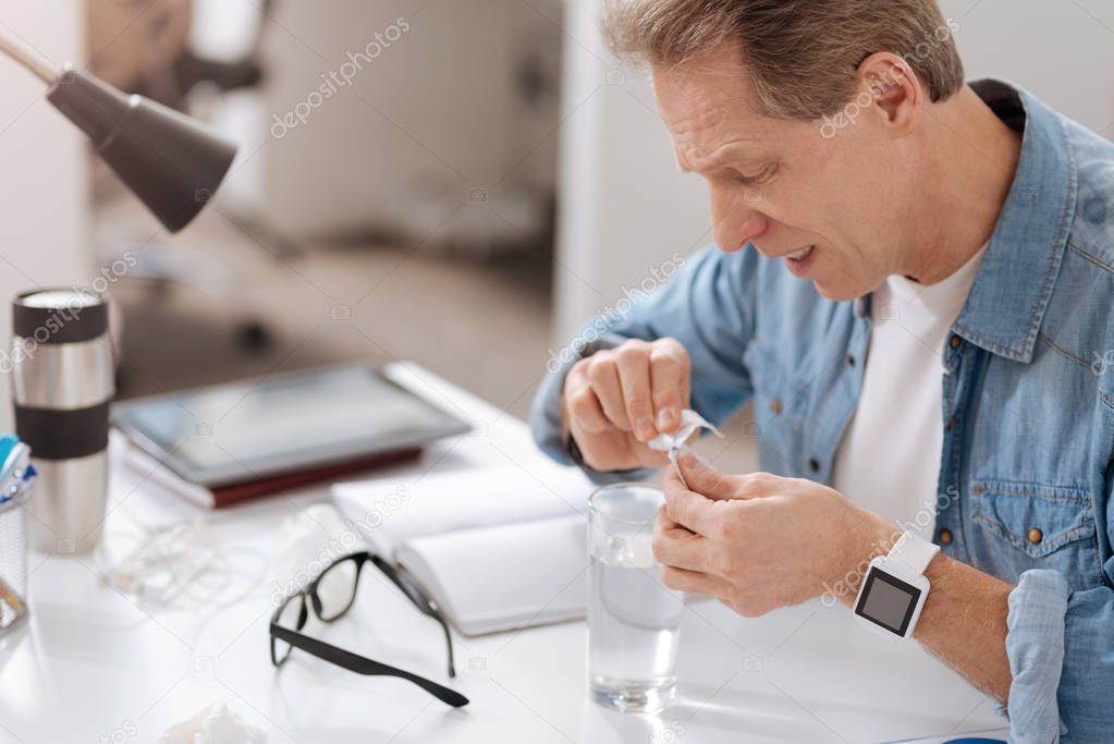 Sick elderly man preparing medicine