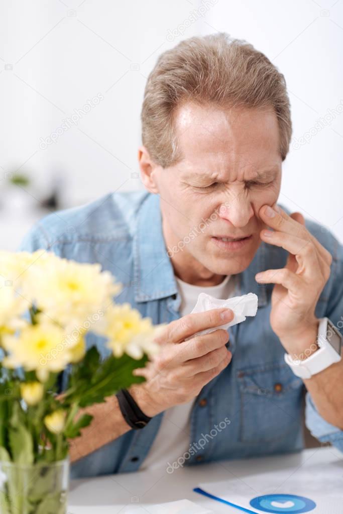 Disturbed man having allergy on flowers