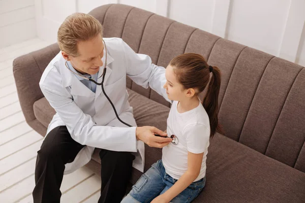 Médico competente e agradável usando seu estetoscópio — Fotografia de Stock