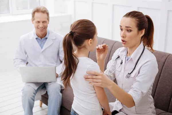 Freundliche nette Ärztin, die kleine Patientin bittet, ihren Mund zu öffnen — Stockfoto