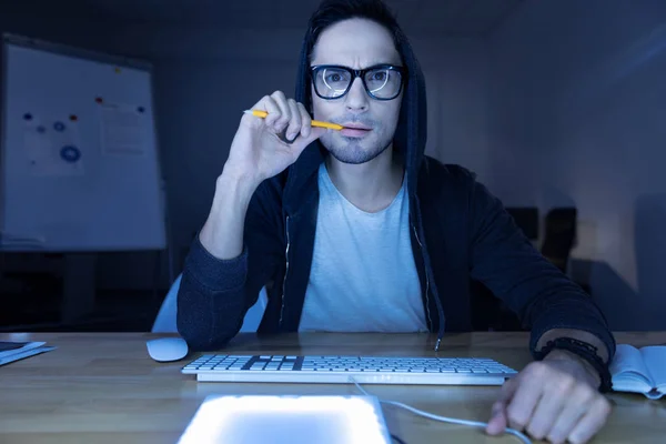 Handsome genius hacker biting a pencil — Stock Photo, Image