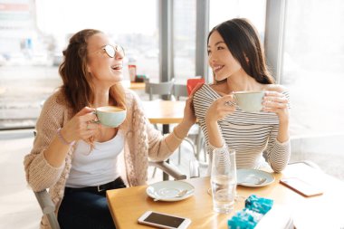 Kafede oturan olumlu gülümseyen arkadaşlar