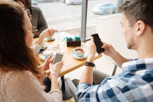 Amis positifs utilisant des smartphones dans tha café — Photo