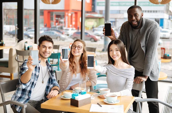 Молодые люди со смартфонами отдыхают в кафе — стоковое фото