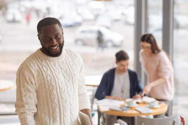 Joven hombre sonriente trabajando con colegas en un café — Foto de Stock