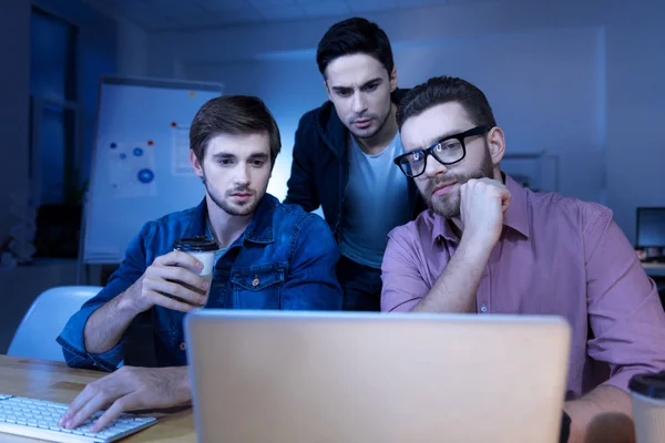 Bonitos homens inteligentes olhando para a tela do laptop — Fotografia de Stock