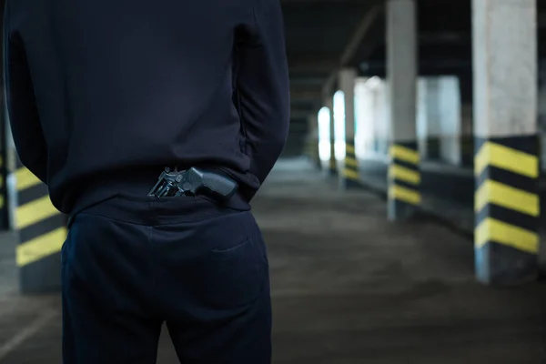 Acercamiento de una pistola guardada detrás de la espalda — Foto de Stock