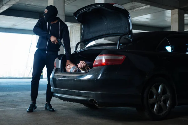 Aggaszt veszélyes bűnözőt, amivel áldozata a autó csomagtartó — Stock Fotó