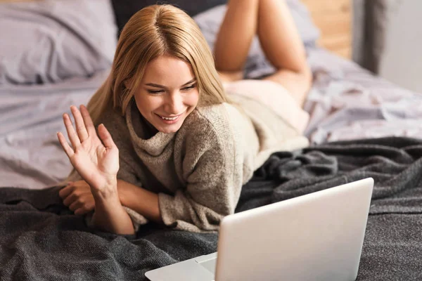 Friendly young woman enjoying conversation via Internet at home
