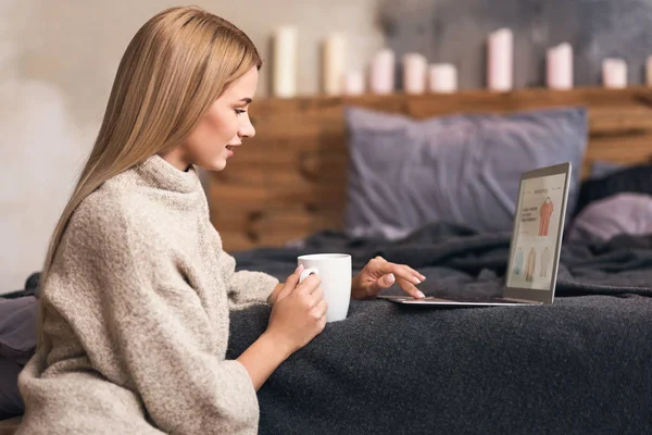 Atraktivní mladá žena se těší online nakupování v ložnici — Stock fotografie