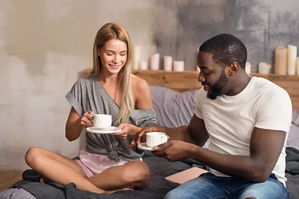 Encantada pareja internacional bebiendo té en casa — Foto de Stock