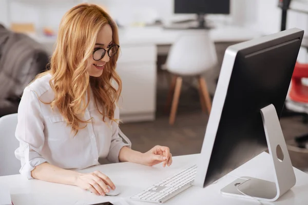 Optimistische junge Sekretärin, die im Büro an dem Projekt arbeitet — Stockfoto