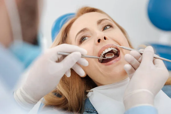 Escrupuloso dentista competente limpiando los dientes de los pacientes — Foto de Stock