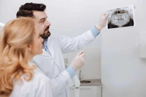 Sábio dentista cuidadoso mostrando uma varredura para seu colega — Fotografia de Stock
