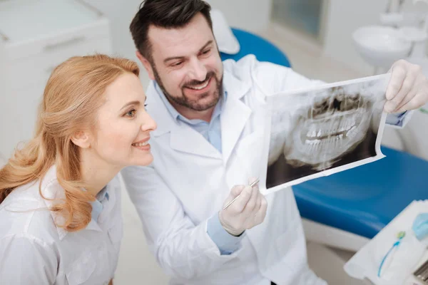 Encantador jovem dentista compartilhando o progresso de seu paciente — Fotografia de Stock