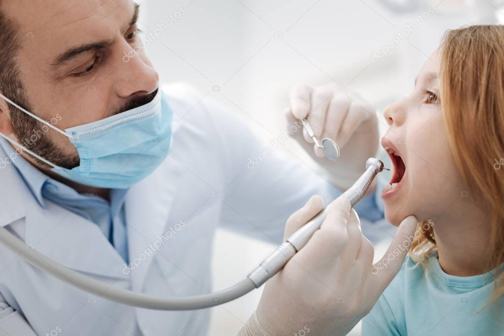 Professional child dentist doing a regular procedure