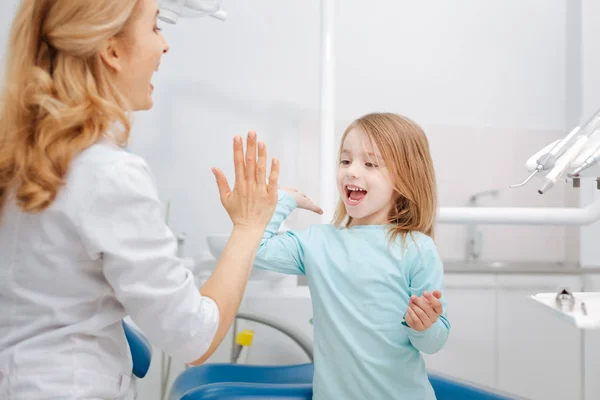Criativa profissional dentista dando a seu pequeno paciente um alto cinco — Fotografia de Stock
