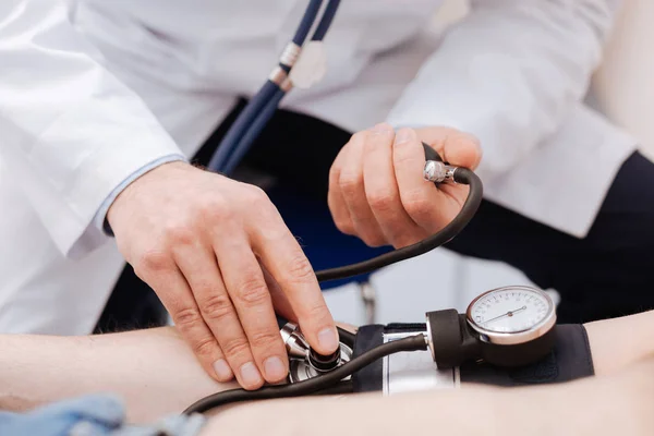 Médico competente preciso aplicando sensor de pressão arterial — Fotografia de Stock