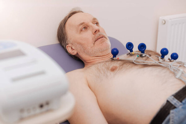 Focused calm man having his heart rate examined
